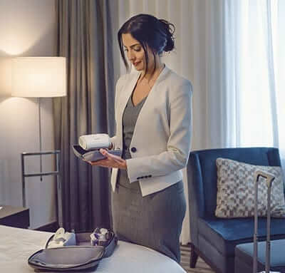 Une femme regarde sa Airmini CPAP tout en faisant ses valises pour un voyage
