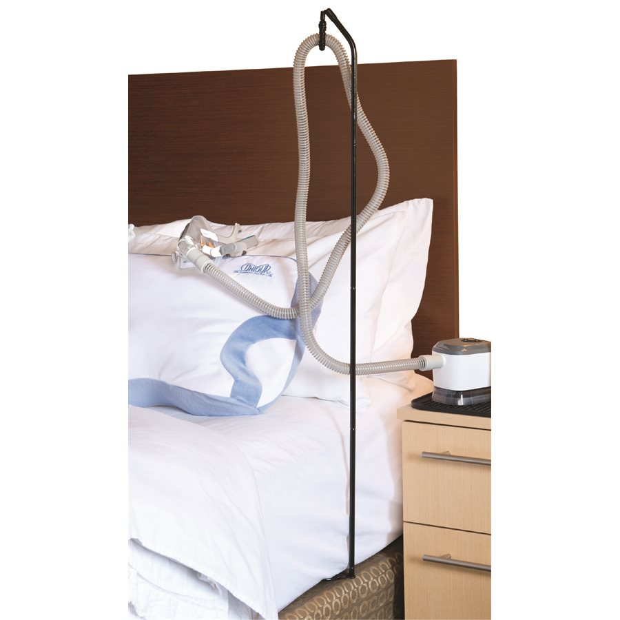 Hose lift set up in a bed demonstrating how it fits between mattresses and ruses above mattress to hold the hose next to bed side table is the CPAP